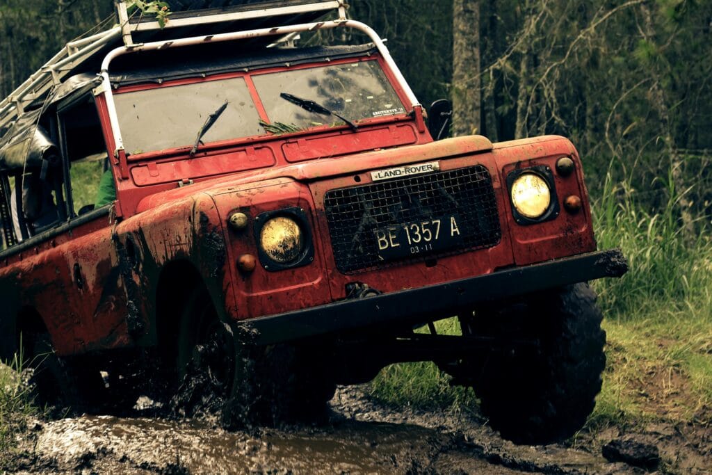 Choosing the right safari vehicle 18 A rugged vintage Land Rover conquers a muddy trail, showcasing off-road capabilities and adventure spirit.