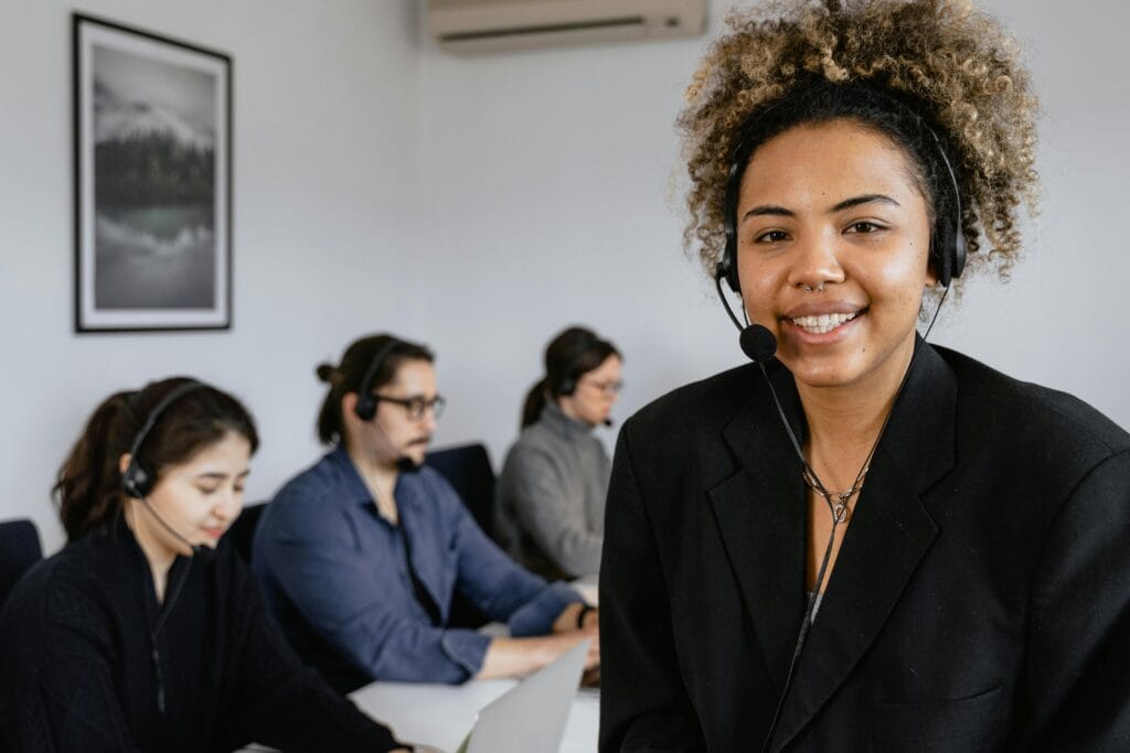 Smiling support agent wearing a headset in a call center environment.