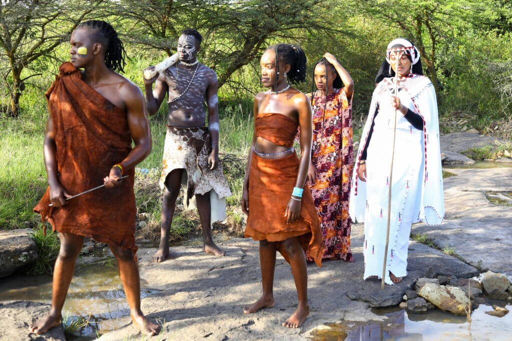 Five people in traditional African tribal attire outdoors, showcasing cultural heritage.