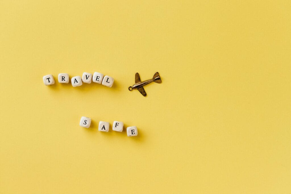 Tips for staying safe in Zanzibar 19 Flat lay of 'Travel Safe' text with airplane pendant on yellow background, evoking travel and safety concepts.