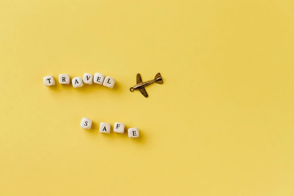 Tips for staying safe in Zanzibar 10 Flat lay of 'Travel Safe' text with airplane pendant on yellow background, evoking travel and safety concepts.