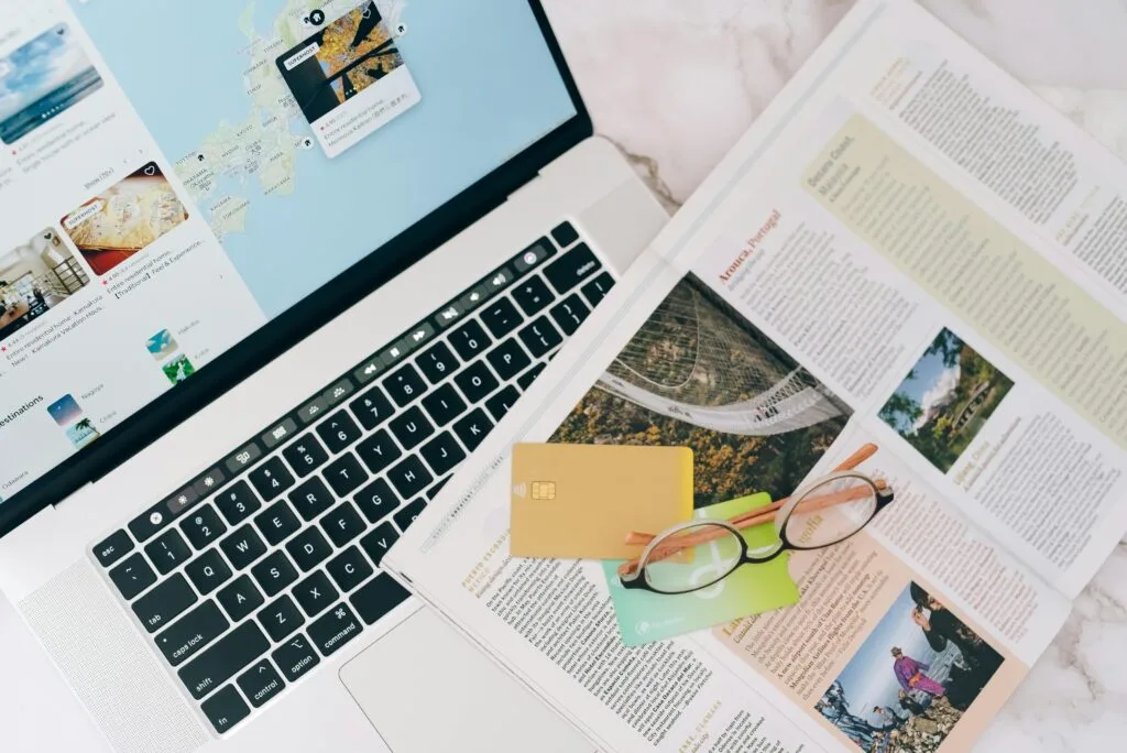 Creating a Zanzibar travel itinerary 13 A top view of travel planning essentials on a laptop with a map, credit cards, and a magazine.