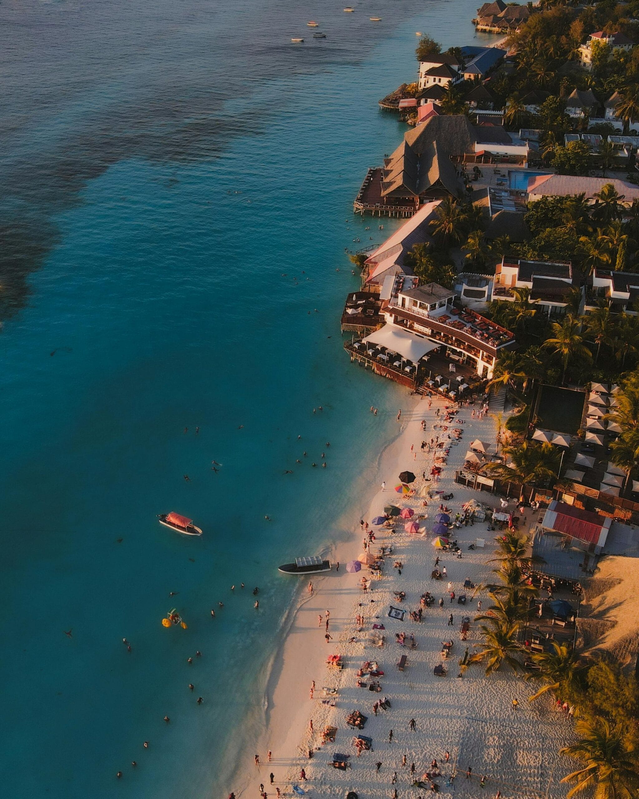 Zanzibar Nature & Ocean Escape: Jozani Forest, Maalum Cave & The Rock Restaurant Day Trip 1 Stunning aerial shot of Nungwi Beach in Tanzania with people enjoying the shore at sunset.