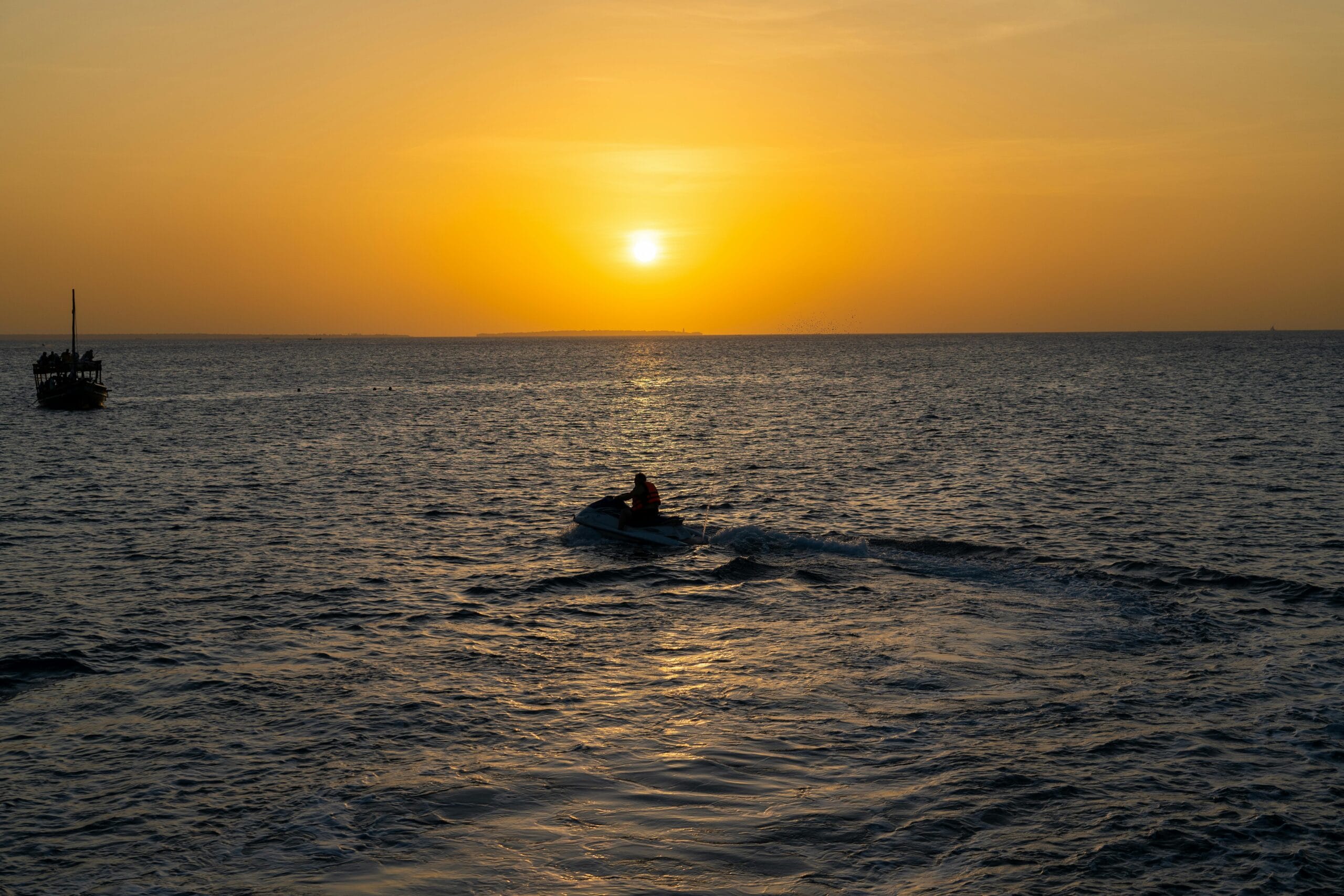 Zanzibar Jet Ski Adventure: Ultimate Ocean Thrill & Coastal Exploration Experience 5 Vivid sunset over the Indian Ocean in Zanzibar with a jet ski silhouette.