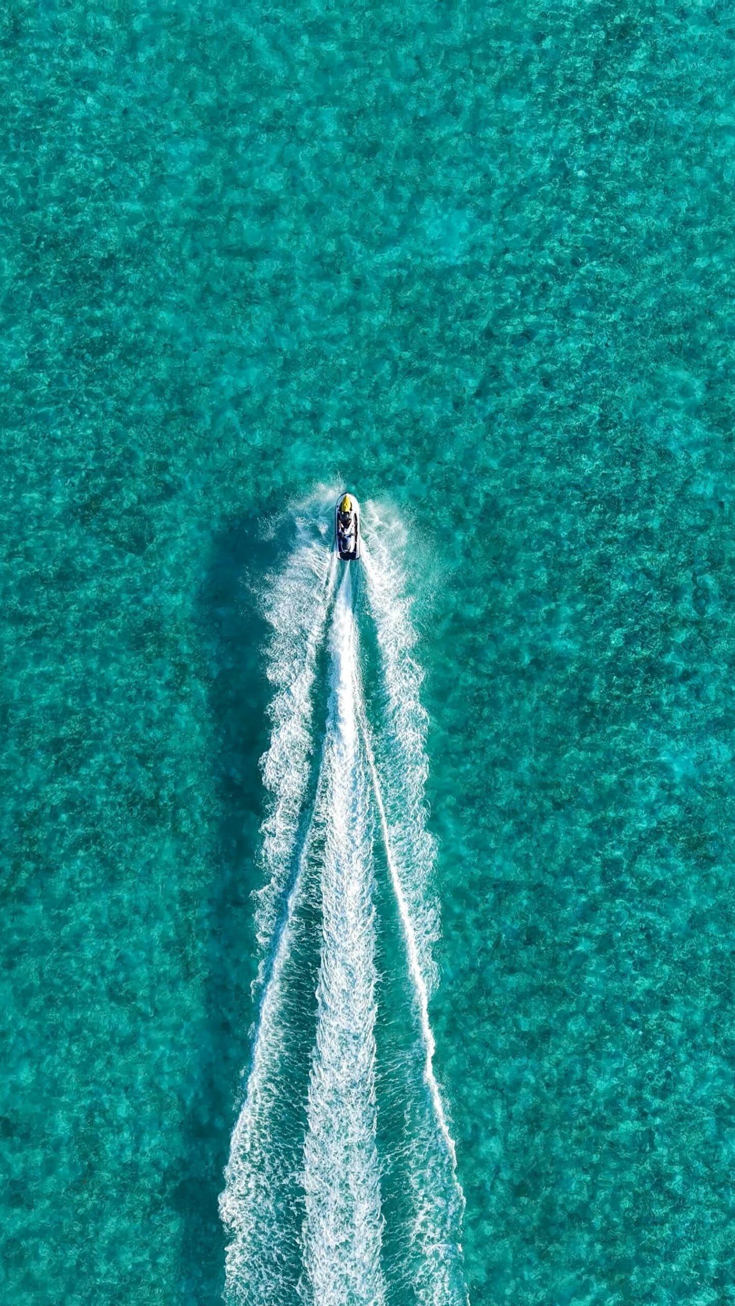 Zanzibar Jet Ski Adventure: Ultimate Ocean Thrill & Coastal Exploration Experience 2 Drone shot of a jet ski creating a white wake on a vibrant turquoise ocean.